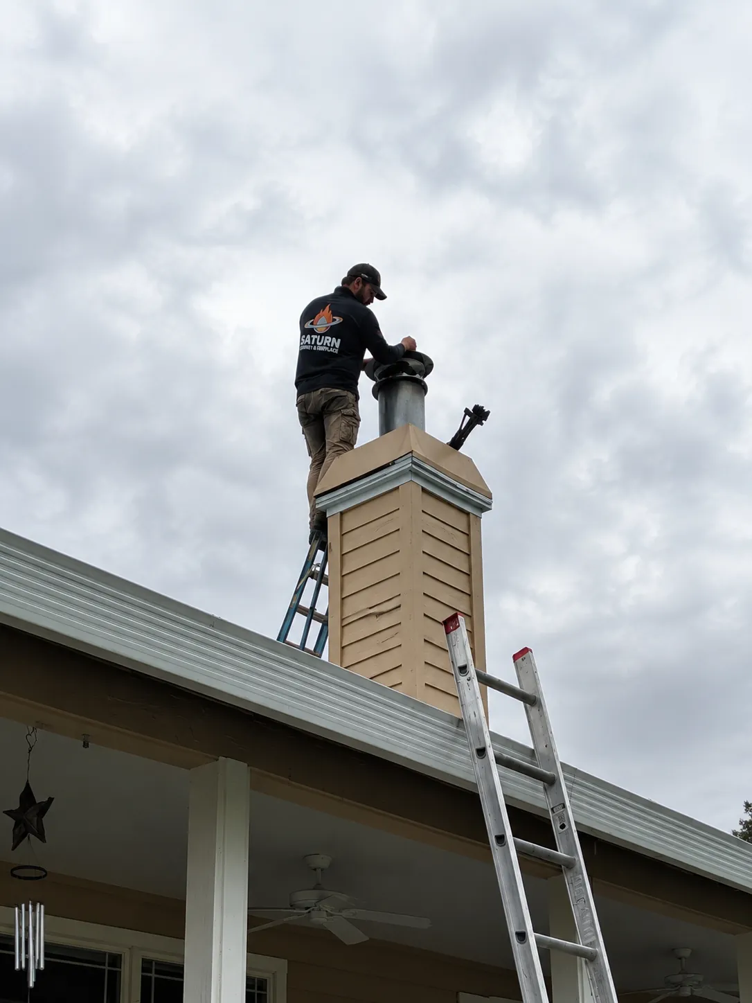 Saturn technician installing a chimney chase cover from a ladder